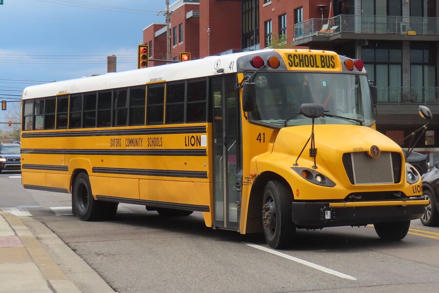 A yellow electric school bus made by Lion Electric parked on a city street